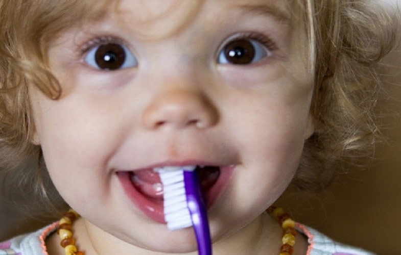 little girl holding toothbrush in her mouth