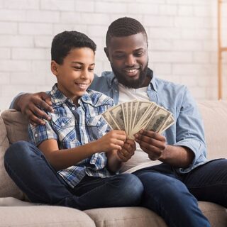 man and boy sitting together holding American bills