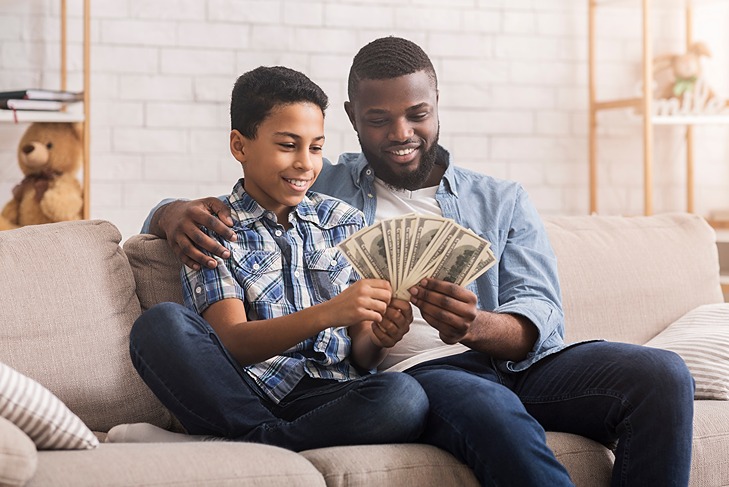 man and boy sitting together holding American bills